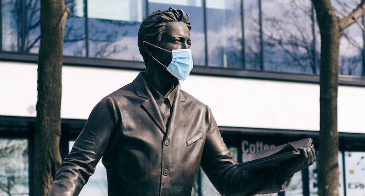 bronze statue of suited man with face mask